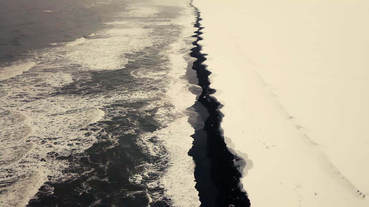 영화 같은 드론 움직임은 눈 덮인 조건에서 드론으로 촬영한 아이슬란드의 검은 모래 해변을 보여줍니다.