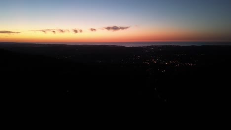 Ascain-France-coastal-town-at-dusk-with-lights-illuminating-the-village-near-the-Atlantic-Ocean,-Aerial-flyover-shot