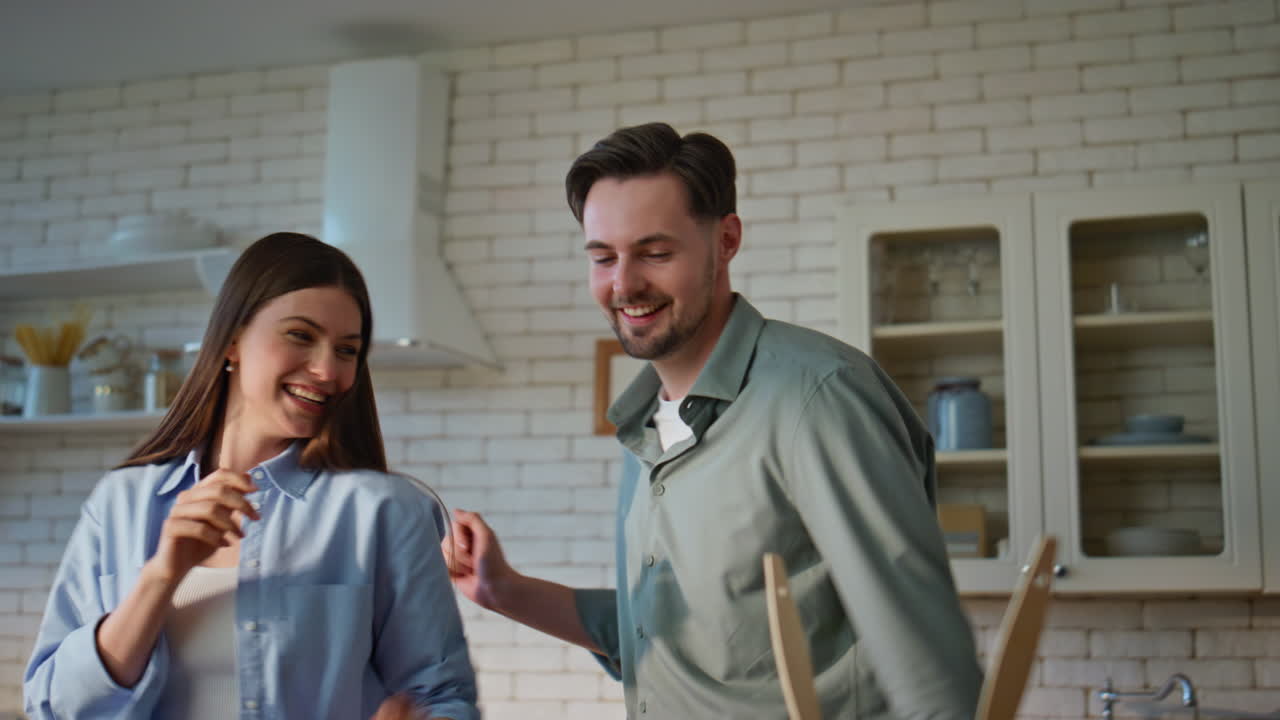 Laughing couple dancing cuisine together closeup. Cheerful friends rejoicing