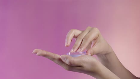 close up of a young woman's hands opening a blush case, make up, cosmetics, on a moving pink background
