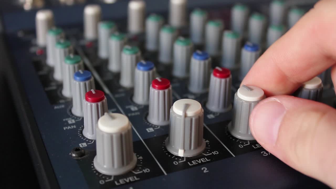 Close-Up of Hand Adjusting Knobs on a Sound Mixer
