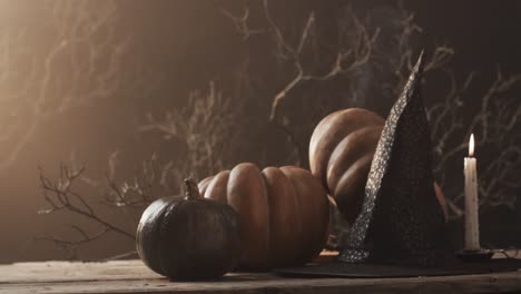 Video-of-halloween-pumpkins,-hat,-candle-and-copy-space-on-brown-background