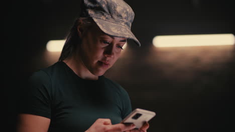 woman in military uniform using smartphone