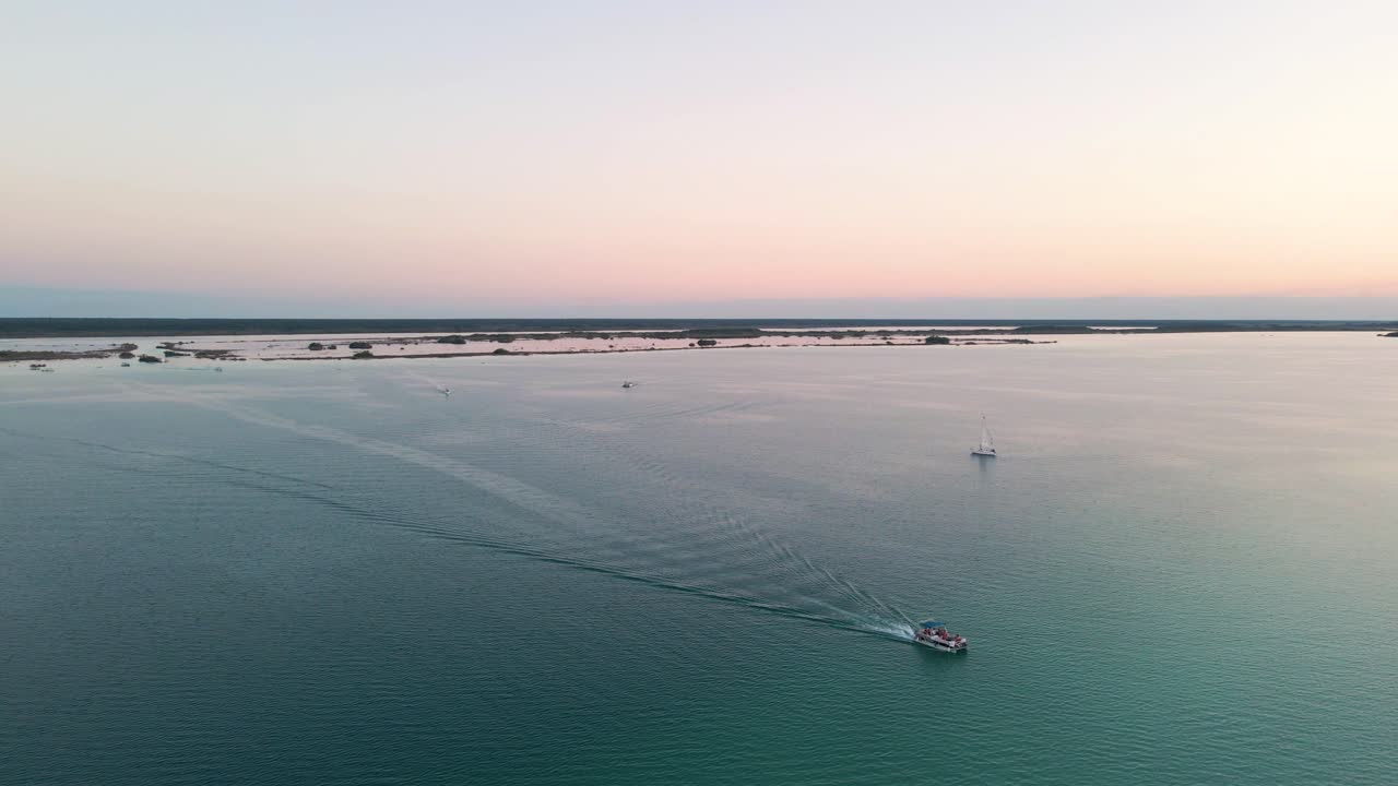 멕시코 바칼라르에 위치한 부두로 돌아가는 요트와 범선이 4k로 일몰 동안 7색 석호의 아름다운 장면을 촬영하는 광각