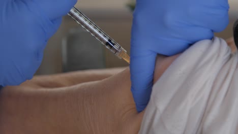 primer plano del brazo de un paciente anciano mientras recibe la vacuna covid-19