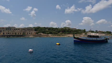Shot-from-tourist-boat-of-old-historic-buildings-along-the-sea-shore-of-Valletta,-Malta-on-a-sunny-day