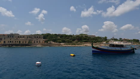 shot from tourist boat of old historic buildings along the sea shore of valletta, malta on a sunny day