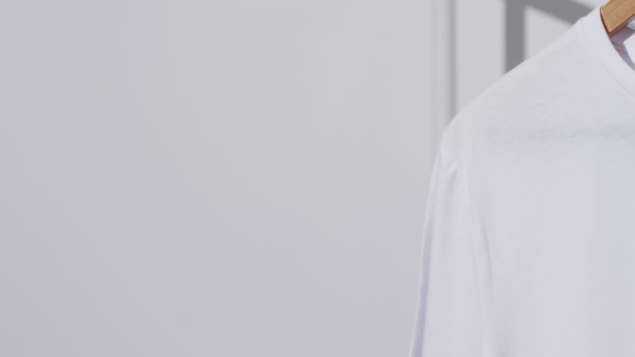 video de camiseta blanca con etiqueta en el colgador y espacio de copia en fondo blanco