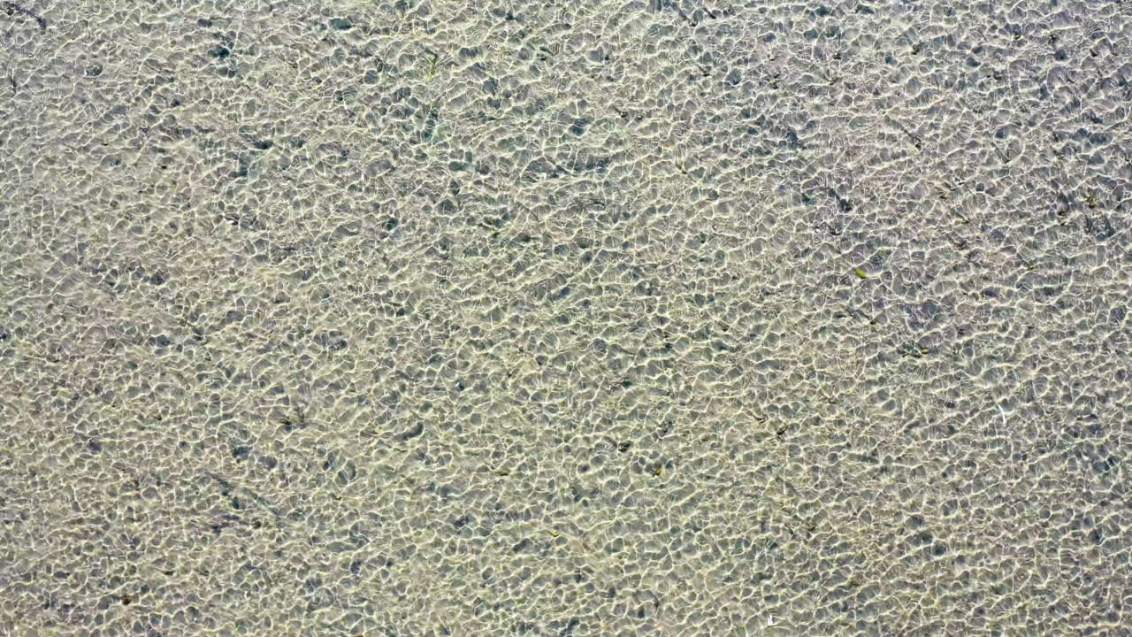 antena de drones de playa oceánica poco profunda y arena con olas soplando en el viento