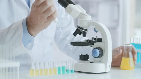 Bearded-Caucasian-male-researcher-wearing-protective-glasses-and-working-with-a-microscope-spbas.-scientist-using-microscope-in-a-laboratory.-Search-for-coronavirus-vaccine.-High-quality-4k-footage