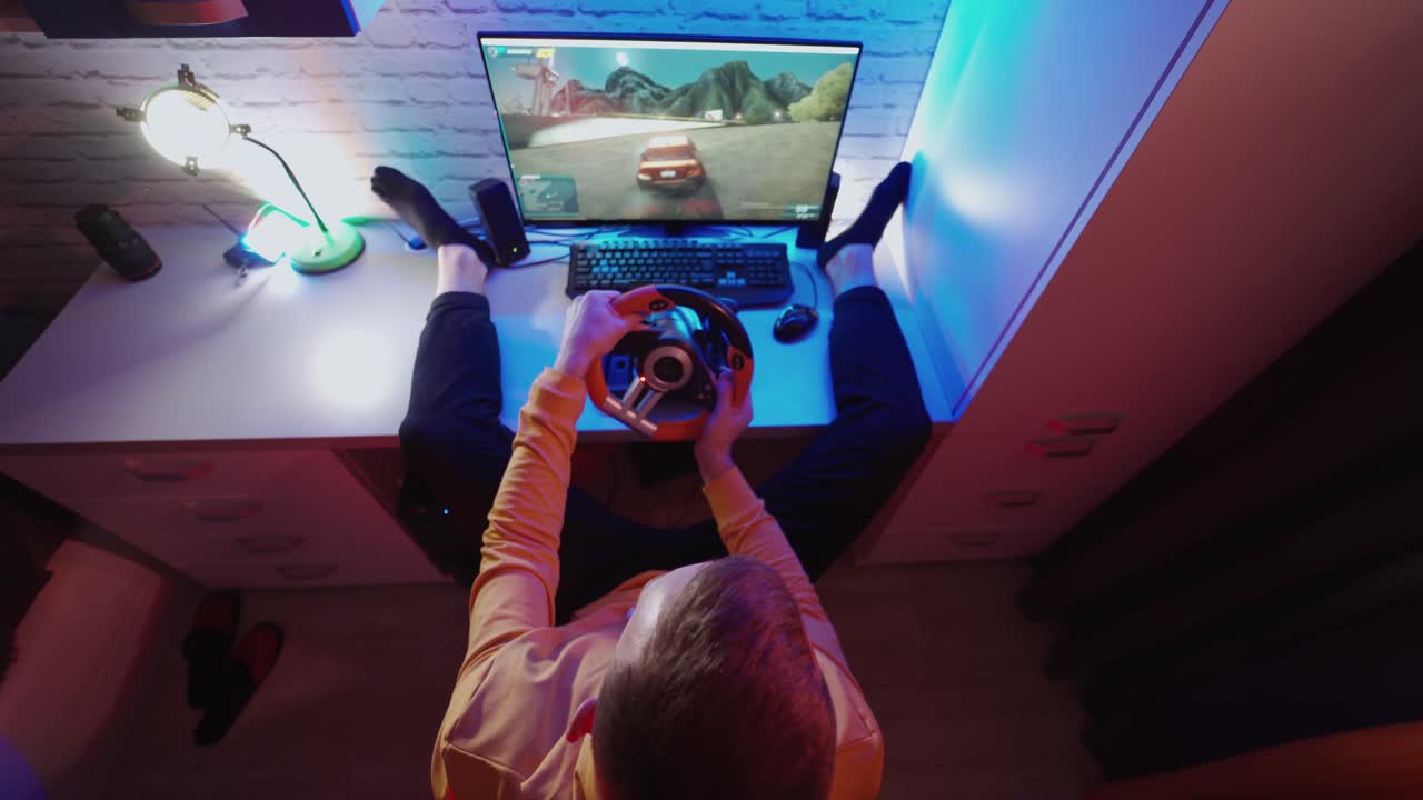 Uomo che gioca a un videogioco sul computer. Vista dall'alto di un gamer che usa un volante da gaming e gioca a un simulatore di guida automobilistica.