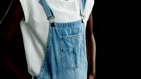 Androgynous-man-in-dungaree-posing-against-black-background