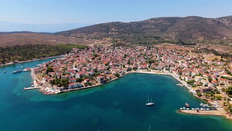 drone establishing over galaxidi harbor with clustered homes along coastline and deep blue sea