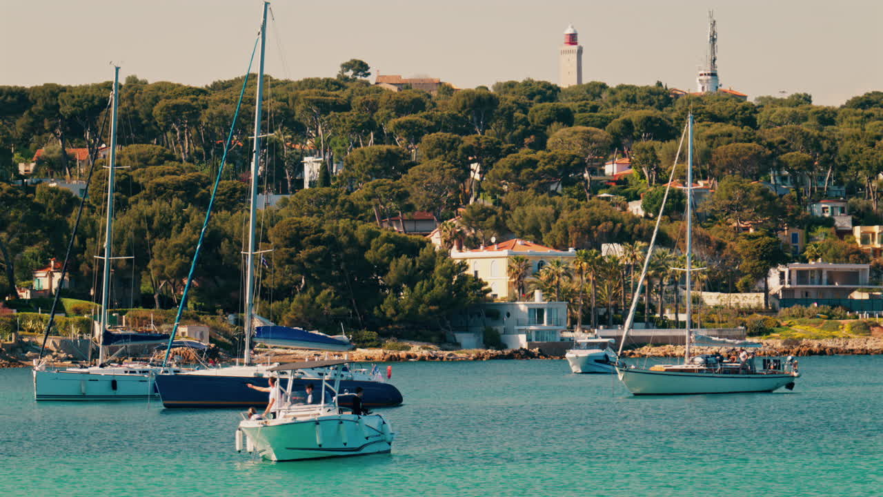 Boats docked on the sea with villas surrounded by greenery in the background