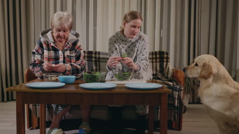 grandmother and granddaughter making salad with dog