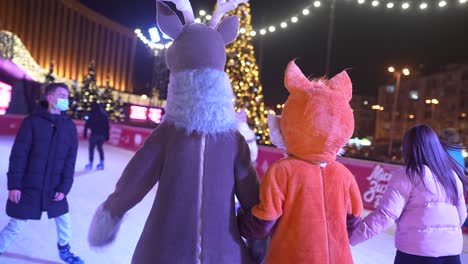 kids in deer and fox costumes ice skating at night