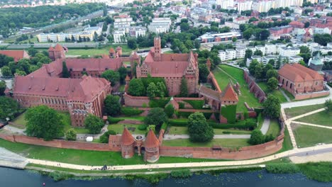 drone footage over malbork castle, medieval red-brick architecture and lush surroundings. malbork, poland