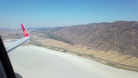 in daylight, a scenic shot is captured from the window of a turkish airlines plane, showcasing the view of acigol and the adjacent hills in denizli cardak