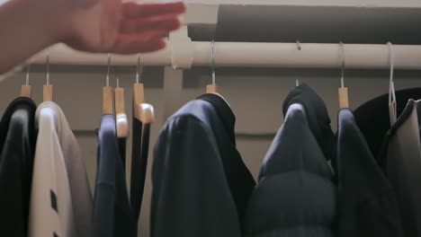 person putting a suit on a clothing rack with clothes