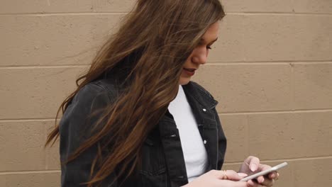 Steadicam-shot-of-a-gorgeous,young,-brunette-college-teenager-texting-on-a-cell-phone-while-smiling