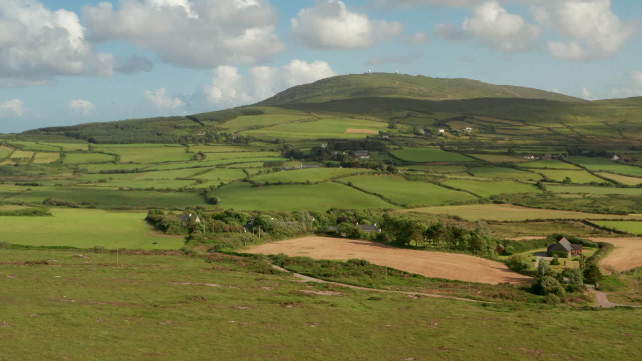 un deslizador aéreo disparado sobre tierras de cultivo verdes en una ladera de una colina en irlanda