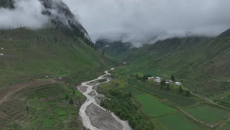 accedendo y luego siguiendo el disparo del avión no tripulado sobre el tranquilizador lago y el exuberante valle verde en la zona norte de pakistán en un día nublado