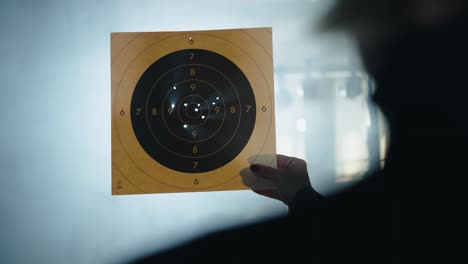 marksman analyzing shooting accuracy with paper target in mist