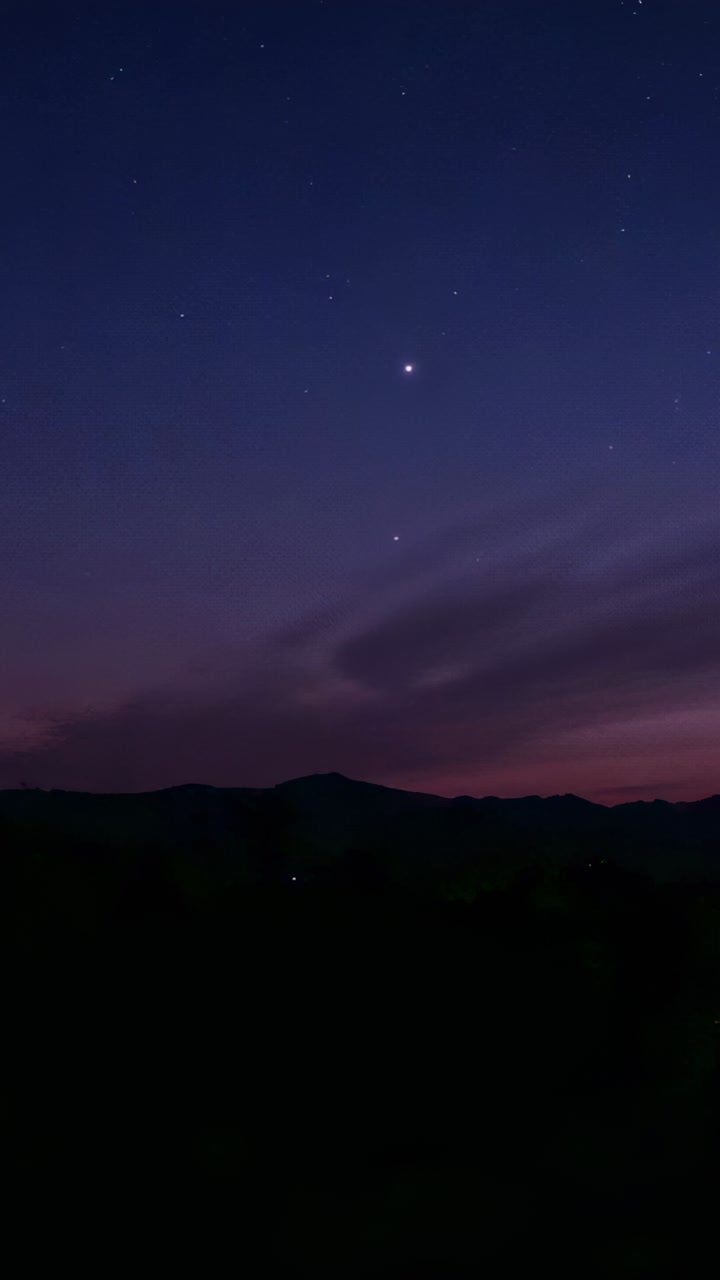 Video verticale: il crepuscolo che cala porta alla luce una coppia di stelle luminose sopra la cresta, appare una luce calda