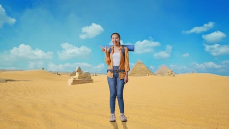 full body of asian female hiker with mountaineering backpack smiling and pointing to side while traveling in pyramid of giza
