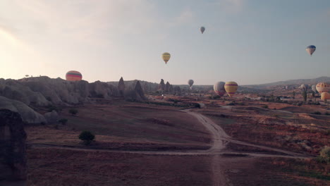 Hot-air-balloons-soar-over-Cappadocia,-viewed-through-a-natural-rock-arch