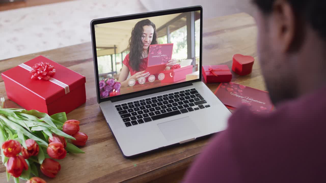 Happy biracial woman with vitiligo reading valentine card on valentine's day video call on laptop