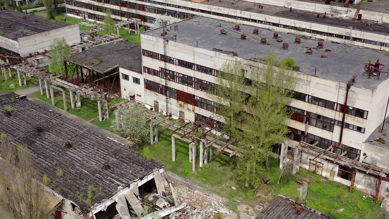 Damaged ancient factory. Broken industrial old plant in springtime. Abandoned place with ruined buildings. Aerial view.