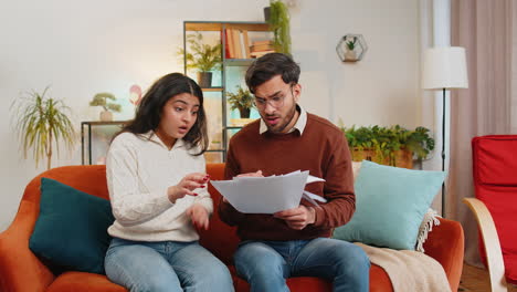 stressed indian family looking at unpaid bank debt bills doing paperwork throws home paper bills