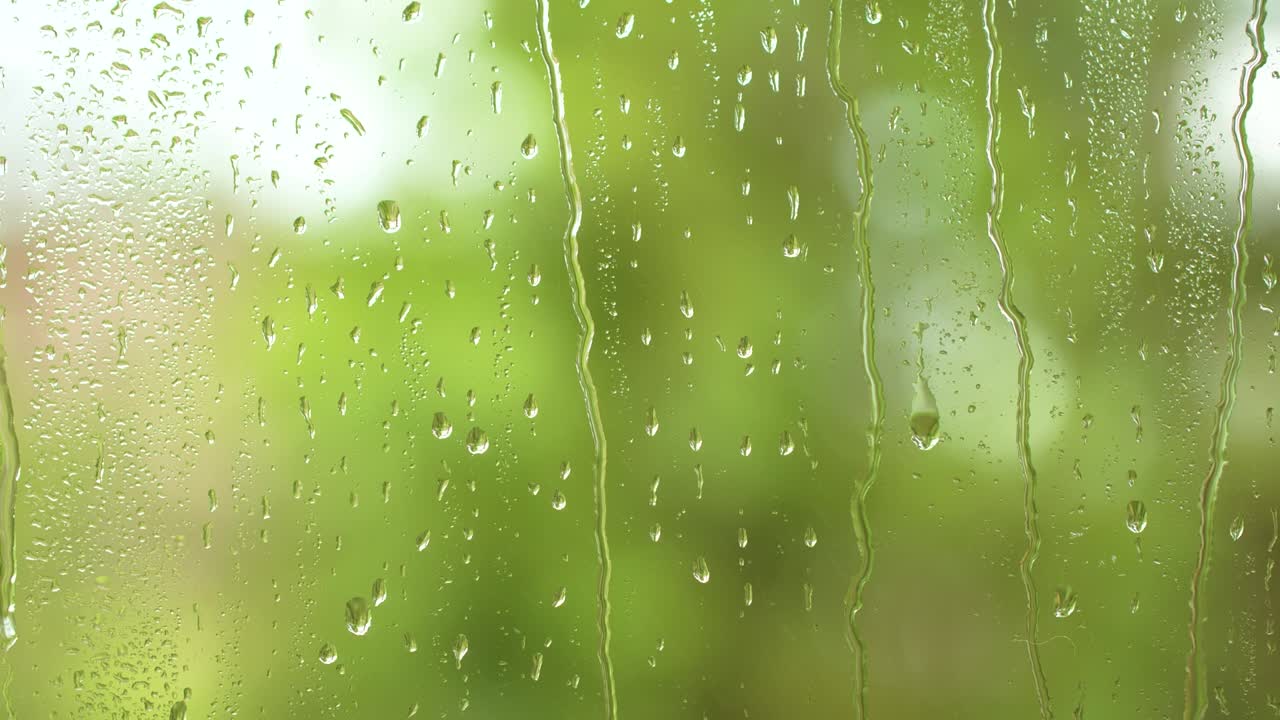 naturaleza lluvia de agua, gotas de lluvia textura en el vidrio de la ventana, árboles verdes borrosos