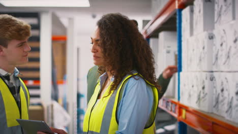 workers with digital tablet in warehouse training male intern standing by shelves