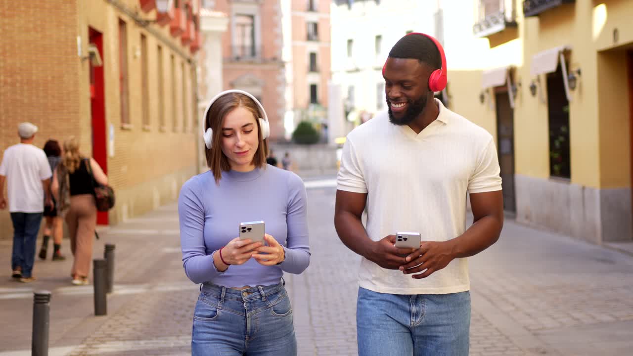 Two young adults listening to music on smartphones in the city