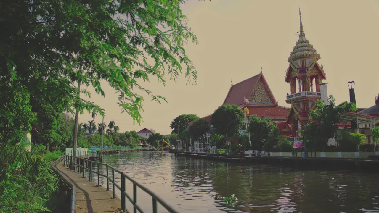 A serene canal view with traditional Thai temple architecture in Bangkok outdoors