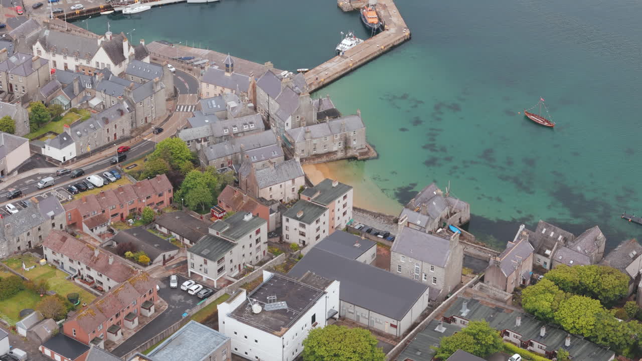 An aerial shot of the harbour town of Lerwick, Shetland in Scotland, sweeping over town area and beach.