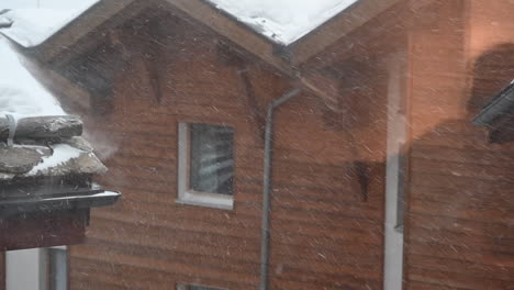 reflection of a person looking out the window at a mountain snowstorm in the swiss alps