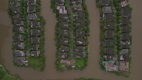 Top-down-view-of-houses-lined-up-on-small-water-bound-islands-in-Hanoi,-Vietnam,-illustrating-the-concept-of-unique-urban-planning-and-harmonious-coexistence-with-nature