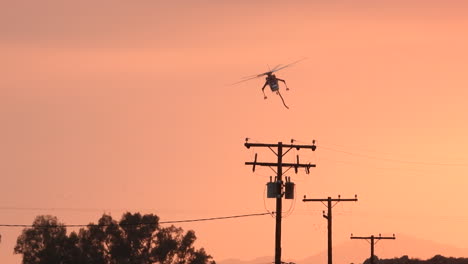 siguiendo a un helicóptero de bomberos que sobrevolaba las líneas eléctricas, durante una puesta de sol brumosa