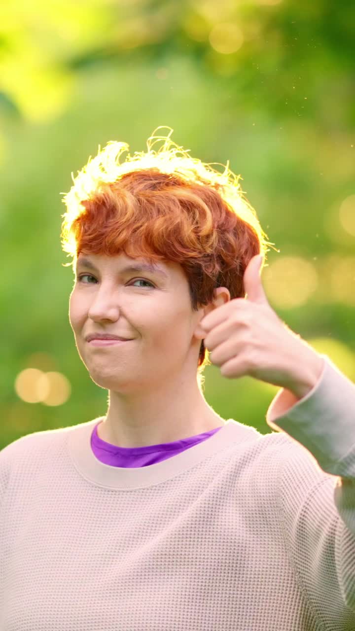 Woman with Red Hair Gives Thumbs Up in Sunny Outdoor Setting