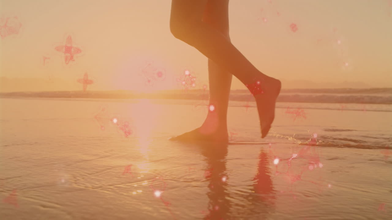 Walking barefoot on beach, person surrounded by glowing red particles at sunset