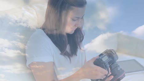 caucasian woman checking pictures in her digital camera against clouds in the sky