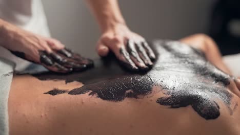 side view, male hands massage back with chocolate, closeup