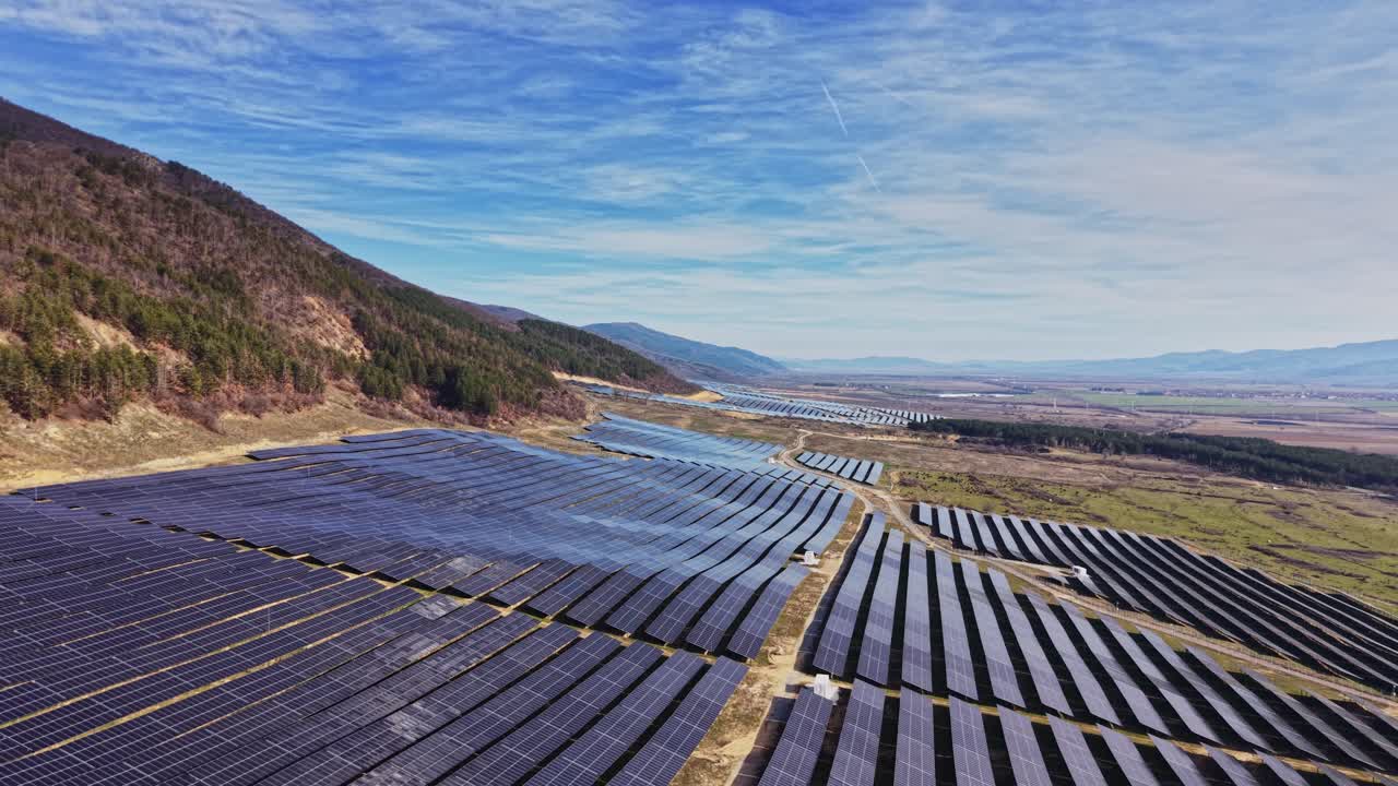 Solpaneler dækker land nær bjerge og marker på en solskinsdag
