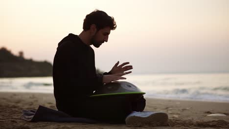 Der-Mann-In-Schwarz-Spielt-Lässig-Und-Sitzt-Allein-Am-Strand-Vor-Dem-Meer