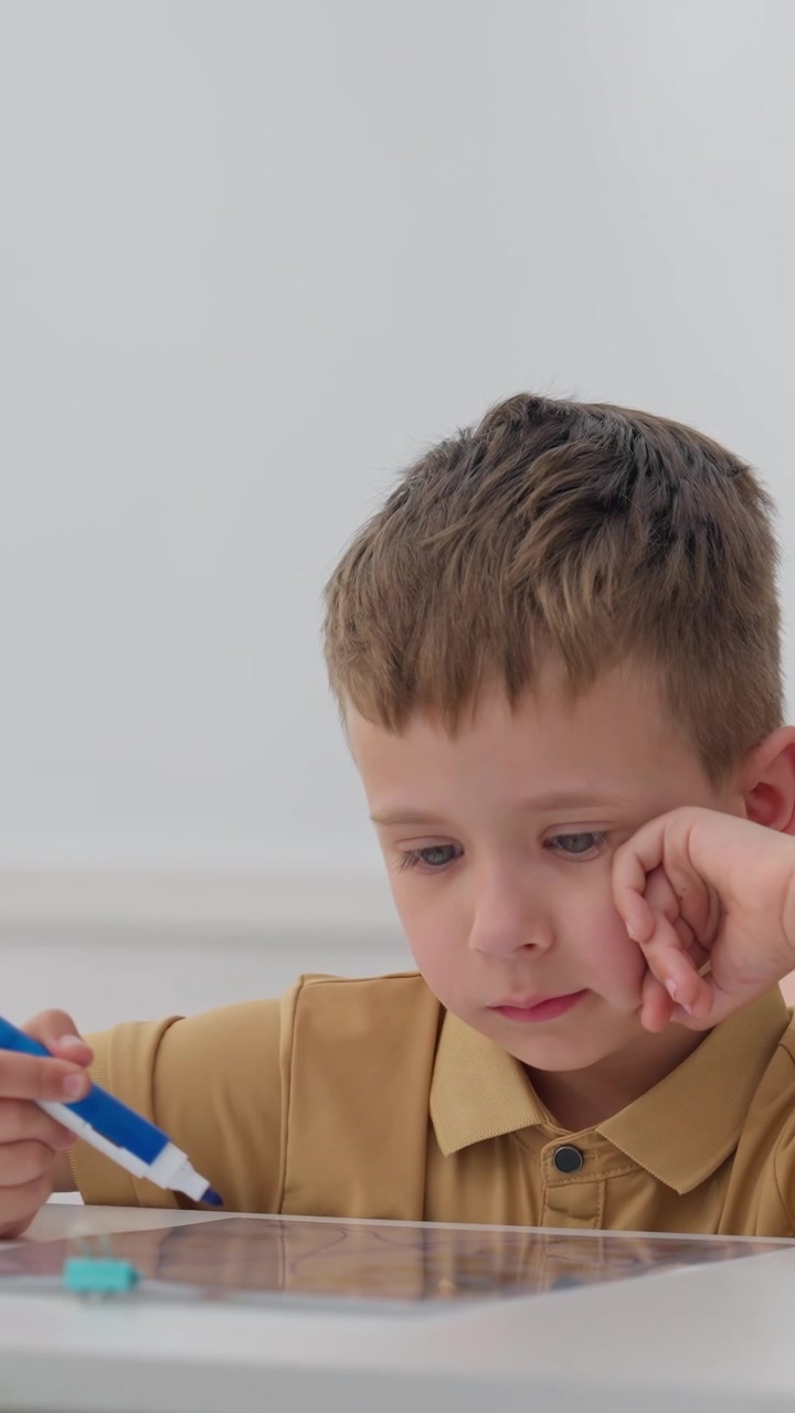 Concentrated Little Boy Drawing on a Clear Board