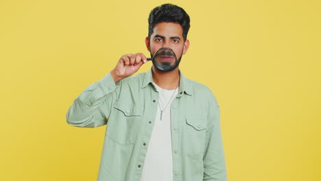 Happy-smiling-Indian-man-holding-magnifier-glass-on-teeth,-health-care,-hygiene,-stomatology-concept