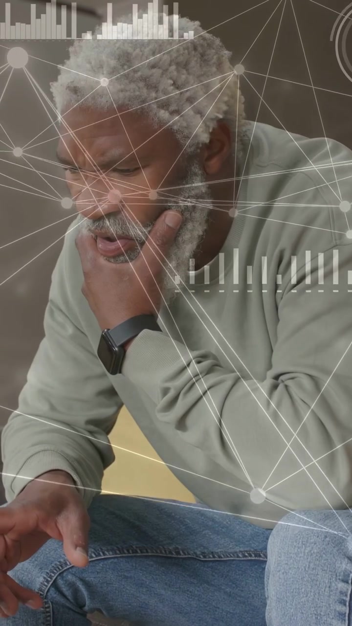 Video verticale: Uomo seduto a casa, con sovrapposizioni che mostrano uno smartwatch e che controlla grafici per la tecnologia.